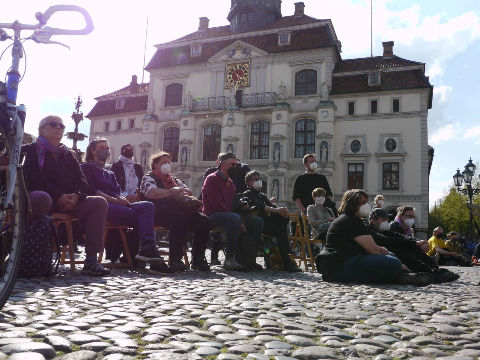 Teilnehmer*innen auf stühle sitzend, im Hintergrund das Rathaus