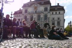 Teilnehmer*innen auf stühle sitzend, im Hintergrund das Rathaus