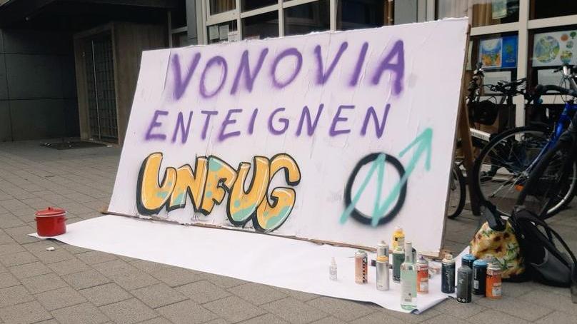 Spraywand mit dem Slogan Vonovia enteignen - Unfug und Besetzungszeichen (Kreis und Pfeil in N Form)